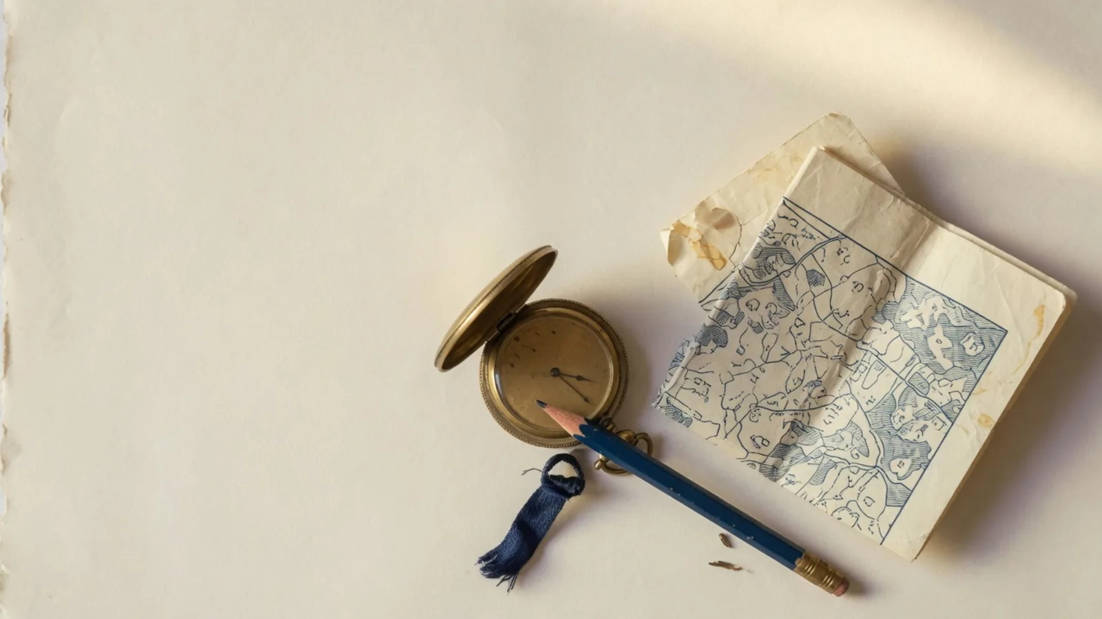 Horloge, potlood en opgevouwen kaart op crèmekleurig papier