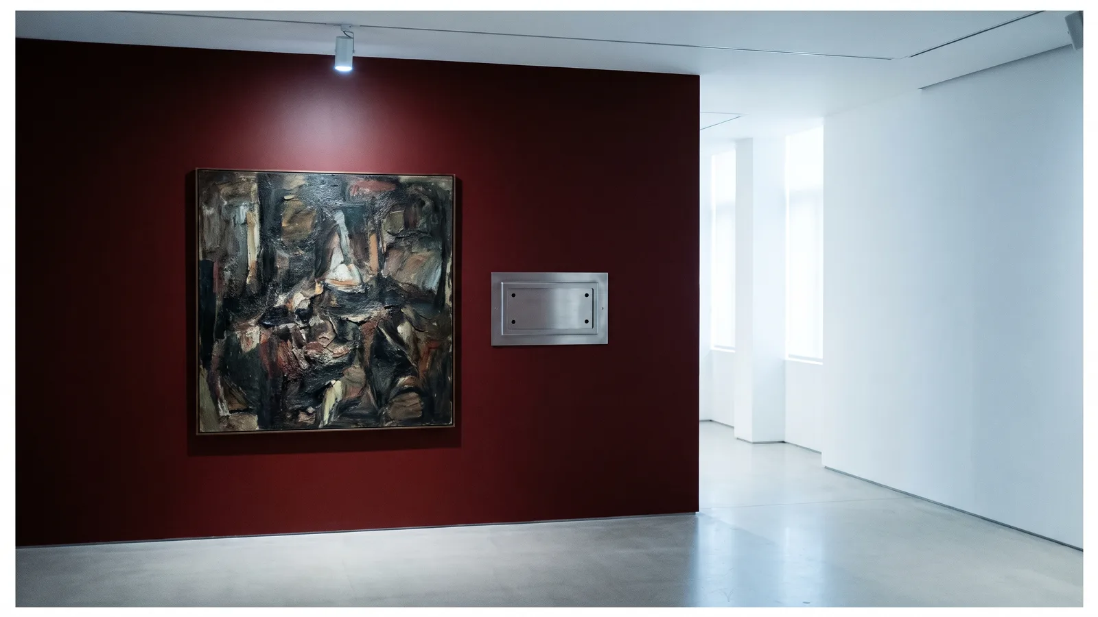 A lit painting on a gallery wall beside an empty label holder with only four pin holes left, one wall painted deep red